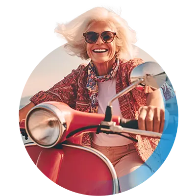 Ältere Dame mit Sonnenbrille sitzt lachend auf einem roten Motorroller.